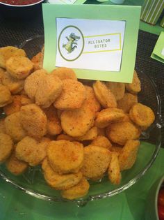 a glass bowl filled with cheetos on top of a green tablecloth covered table