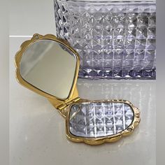 a small mirror sitting on top of a counter next to a glass vase and container