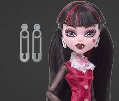 a doll with long black hair and pink eyes is posed in front of hooks, scissors and hooks