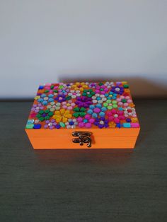 an orange box filled with lots of colorful candies on top of a wooden table