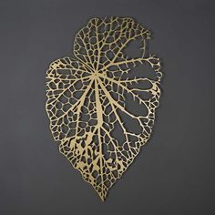 an intricately designed metal piece on a gray background with the shape of a leaf