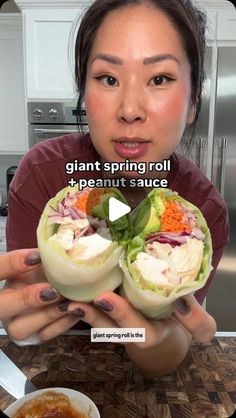 a woman is holding up some food in front of her face with the caption, giant spring roll and peanut sauce