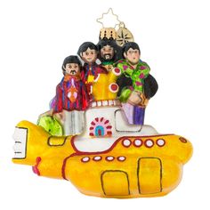 a yellow submarine ornament with beatles on it's side and people standing on top