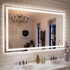 a bathroom vanity with two sinks and a large mirror above it that has lights on