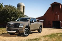 a tan truck parked in front of a red barn and silo on a farm