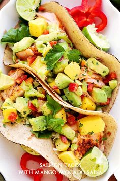 two fish tacos with mango avocado salsa are on a white platter