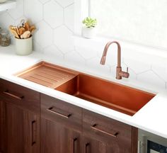 a kitchen sink with copper faucet and wooden cabinets