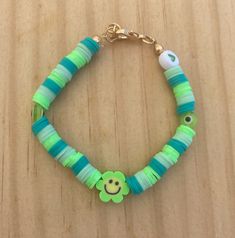 a green and blue bracelet with a smiley face charm