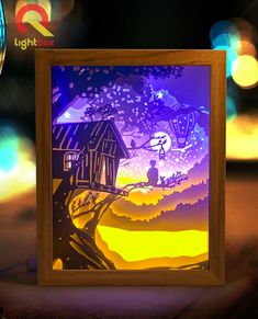 a hand holding a lite up card with a house on the tree at night