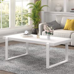 a white coffee table sitting on top of a rug in front of a couch and window