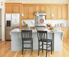 a kitchen with yellow cabinets and two black chairs in front of an island countertop