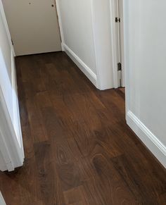 an empty hallway with wood flooring and white door handles on either side of the doorway