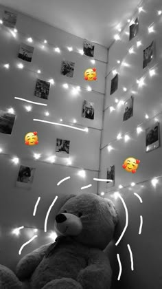 a teddy bear sitting in front of a wall with pictures on it