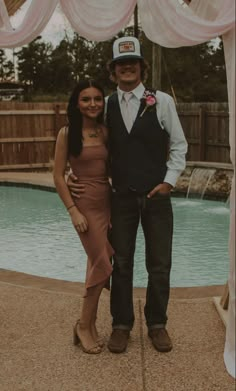 a man and woman standing next to each other in front of a pool