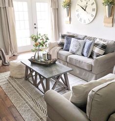 a living room with two couches and a coffee table in front of a clock on the wall