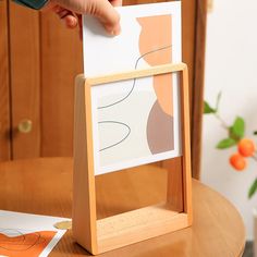 a person holding a piece of paper in front of an easel on a table