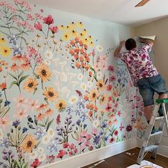 a man is painting a floral wallpaper in a room