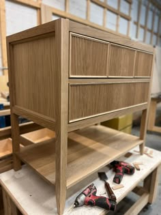 a wooden dresser sitting on top of a table next to other woodworking tools and supplies