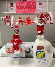 two elfs sitting on top of a washing machine next to a bottle of deterine