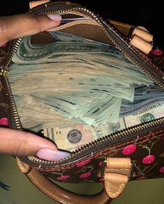 a hand is holding a purse full of money and it's zipped open