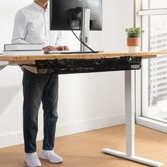 a man standing in front of a desk with a computer on it