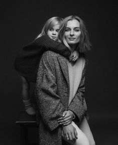 a black and white photo of a woman sitting on a stool with her arm around a child