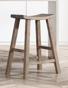 a wooden stool sitting on top of a hard wood floor next to a white counter