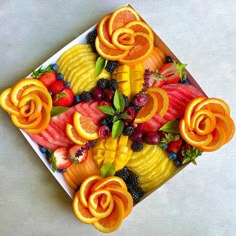 an arrangement of fruit is arranged on a square plate