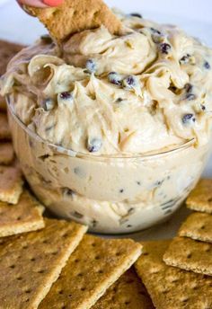 a cracker dipping some food into a bowl filled with cream cheese and chocolate chips