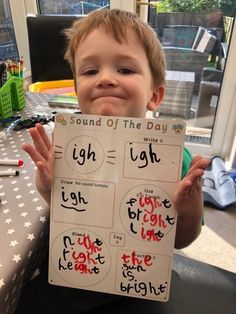 a young boy holding up a sign with words on it that read sound of the day