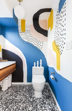 a bathroom with blue, yellow and white paint on the walls next to a toilet