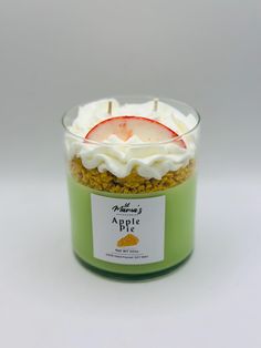 an apple dessert in a glass container with whipped cream on top and a candle sticking out of it