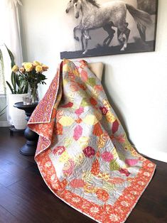 a quilted blanket sitting on top of a chair next to a vase with flowers