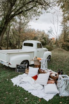 an old white truck parked next to a picnic table with food and drinks on it