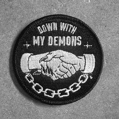 a black and white photo of a patch with the words down with my demons on it