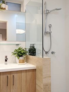 a bathroom with a sink, mirror and shower head mounted to the side of the wall