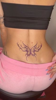 a woman with a butterfly tattoo on her lower back is sitting in a yoga chair