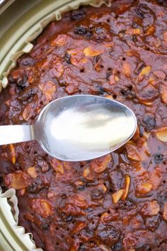 a close up of a spoon in a pot of food with sauce on it and another spoon next to it