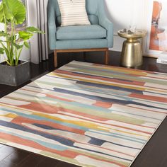 a living room area with a rug, chair and potted plant on the floor