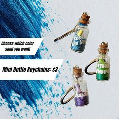 three small bottles filled with different colored sand on top of a white background and the words, choose which color you want mini bottle keychains $ 3