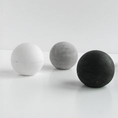 three black and one white balls sitting on top of a table next to each other