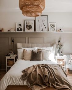 a bed with white sheets and pillows in a bedroom next to pictures on the wall