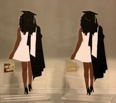 two acrylic cutouts of black women in graduation caps and gowns, one holding a gold purse