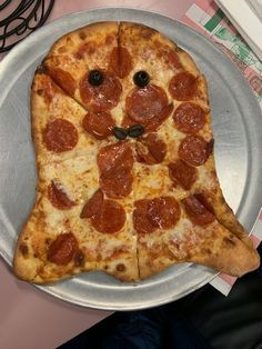 a pizza shaped like a cat on top of a metal plate next to a pile of money