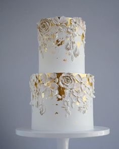 a three tiered cake with white frosting and gold flowers on the bottom layer