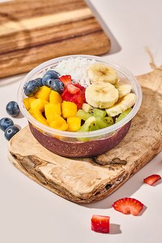 a bowl of fruit is sitting on a cutting board