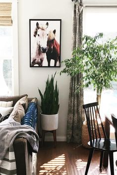 a living room filled with furniture and a painting on the wall next to a window