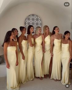 a group of women standing next to each other in long yellow gowns and smiling