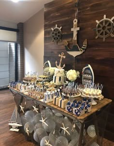 a table topped with lots of cupcakes and cake next to a wooden wall