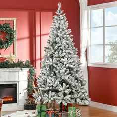 a white christmas tree in a living room with presents around it and a fire place